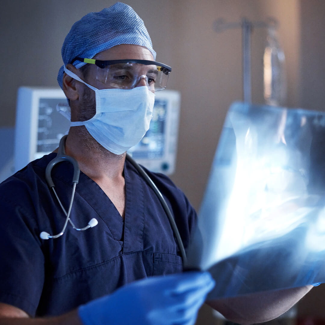 A doctor in scrubs wearing a mask and gloves
