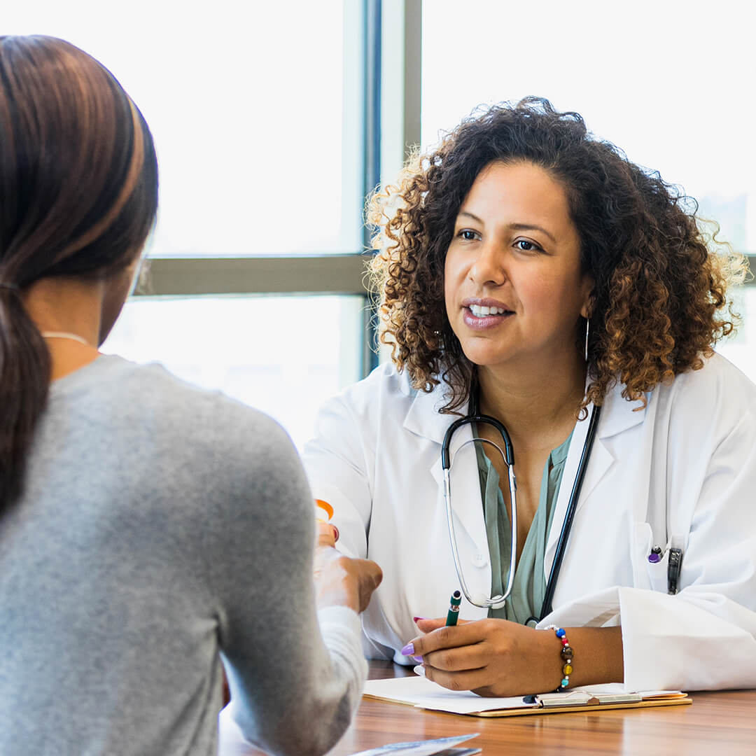 Physician consulting with a patient and reviewing treatment information during a cancer care appointment.
